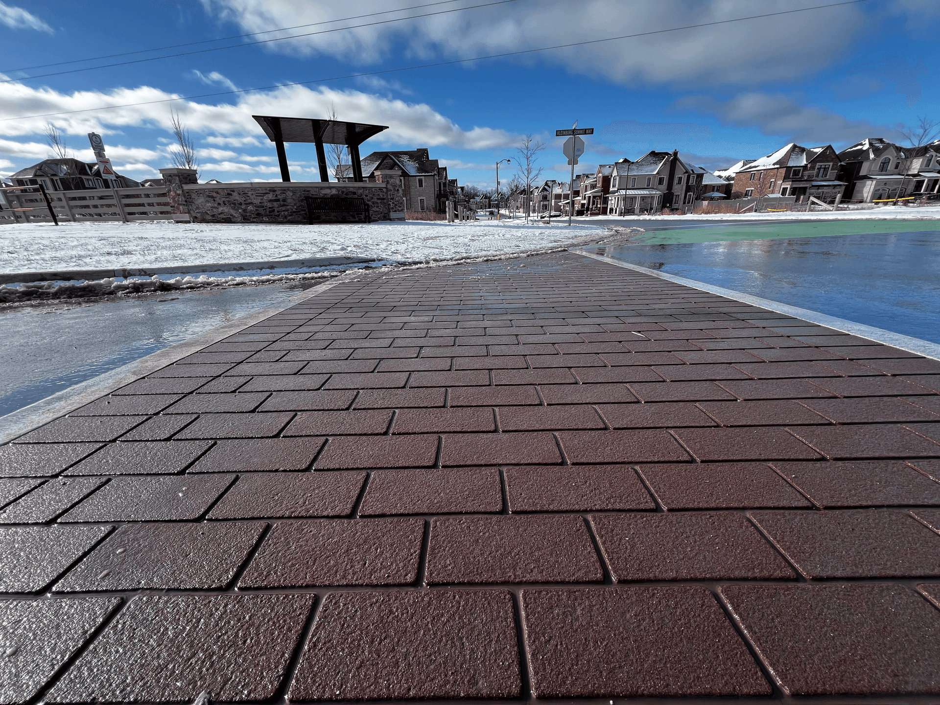 TrafficPatternsXD aggregate-reinforced preformed thermoplastic — red brick-pattern pier walkway on a waterfront promenade, installed by HUB Surface Systems