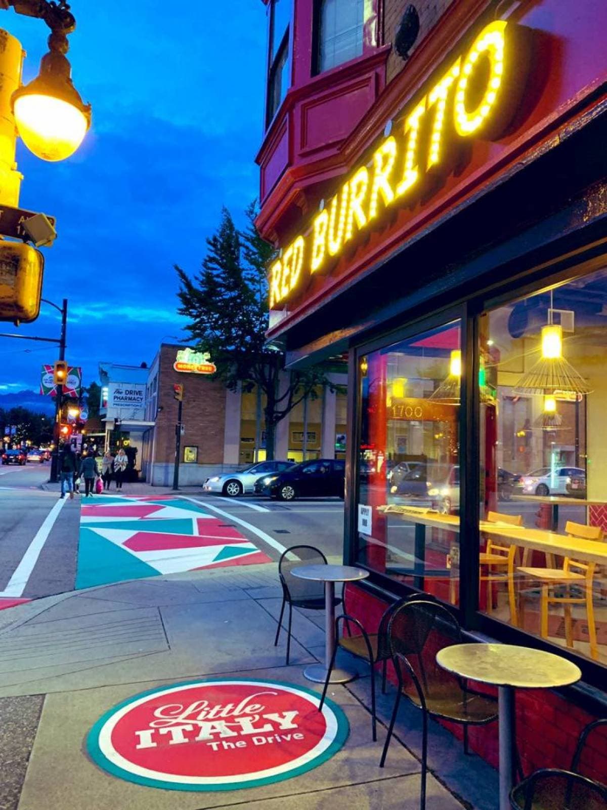 DecoMark Little Italy thermoplastic decal — Commercial Drive community identity marking on Vancouver sidewalk pavement, vibrant street scene at dusk