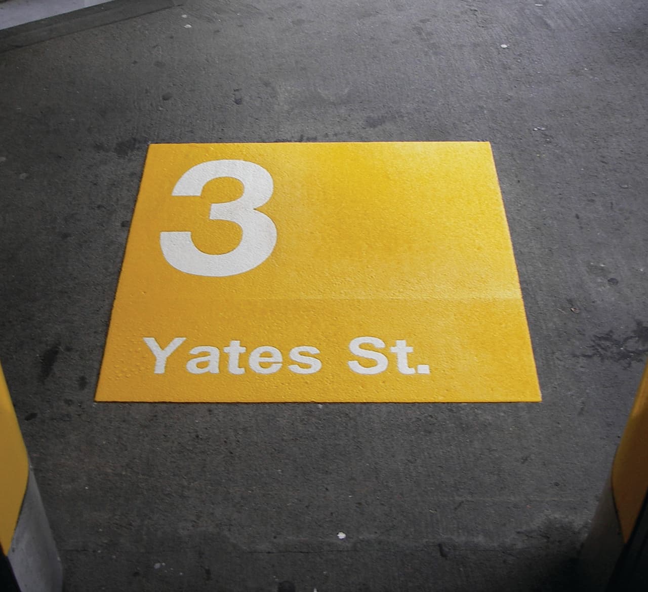 Community branding pavement graphics in custom-colour pavement coating and preformed graphics — a downtown streetscape, Canada