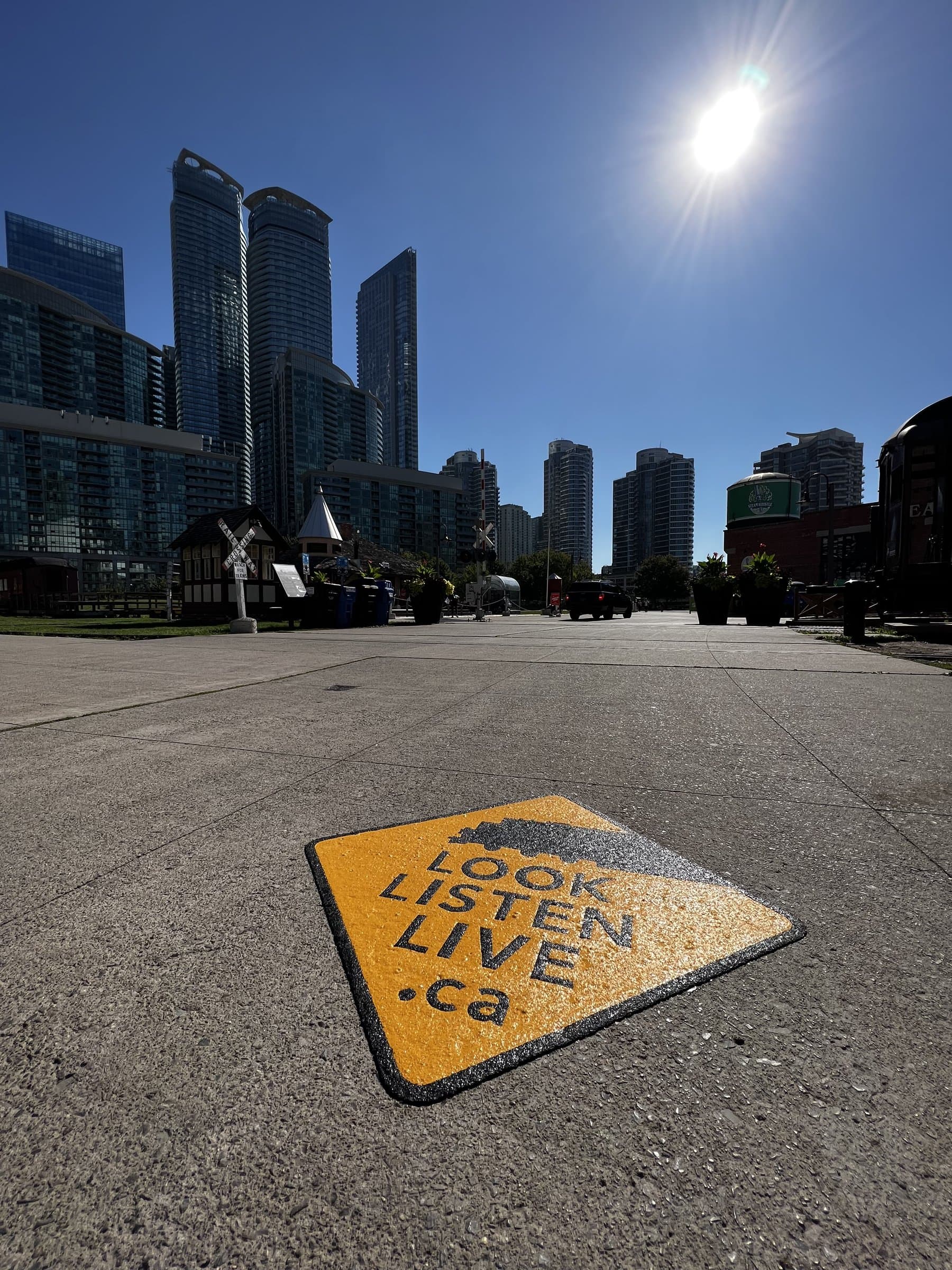 Community branding pavement graphics in custom-colour pavement coating and preformed graphics — a town centre plaza, Canada
