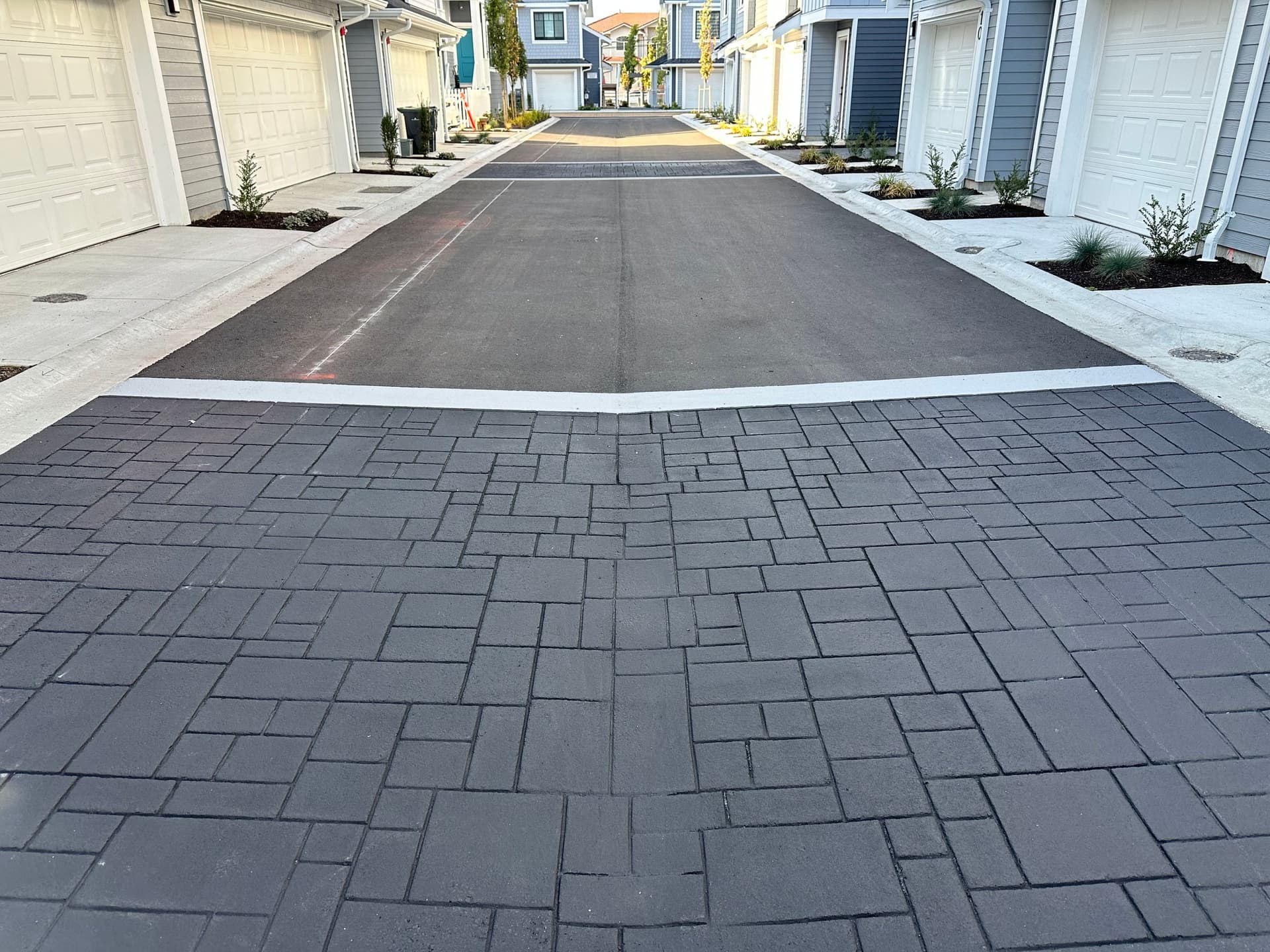 Townhome community paving in stamped asphalt and coloured pavement coating — a strata common entrance, Canada