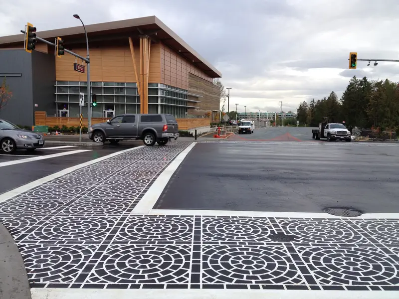 DuraTherm inlaid pattern crosswalk sitting flush with the road beside a wood-clad civic building