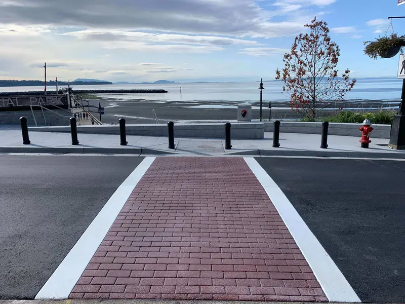 Red brick-pattern TrafficPatternsXD crosswalk with white edge lines at the White Rock Pier, BC